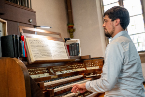 Foto des Organisten Lukas Bajon. Er spielt gerade Orgel.