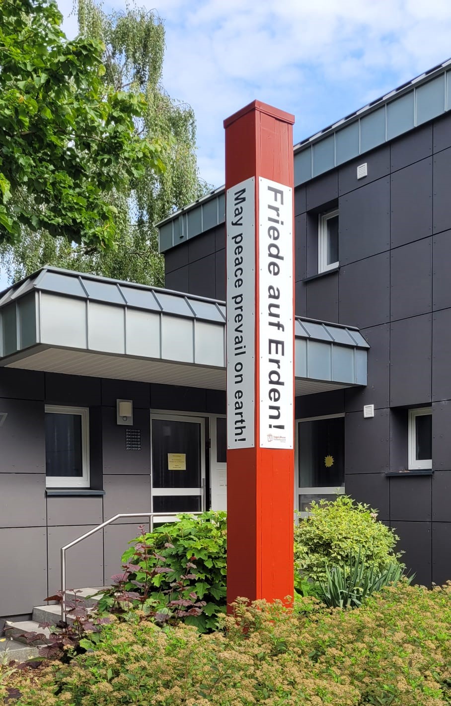 Bild von dem Freidensmahner. Er steht vor dem Pfarrhaus.