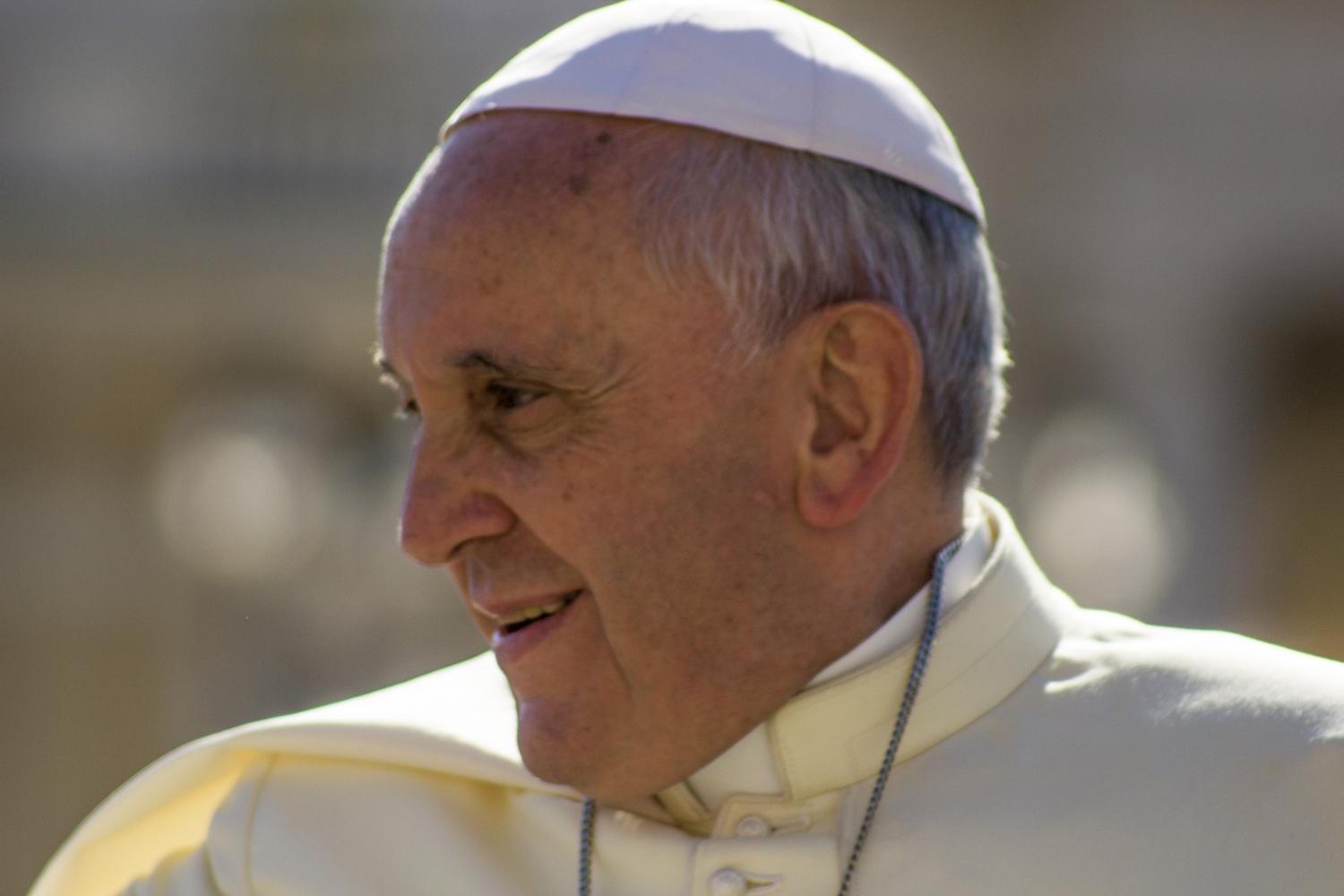 Papst Franziskus in weißem Gewand begrüßt Gläubige auf dem Petersplatz in Rom.